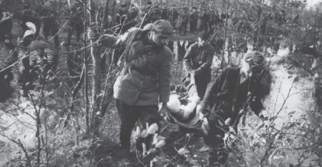 Columna partisana evacuando a un herido por una zona pantanosa