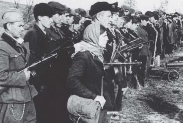 En esta imagen se observa la variedad de trajes y uniformes de los combatientes de la guerrilla. La mujer es una enfermera que lleva una bolsa de lona con una cruz roja