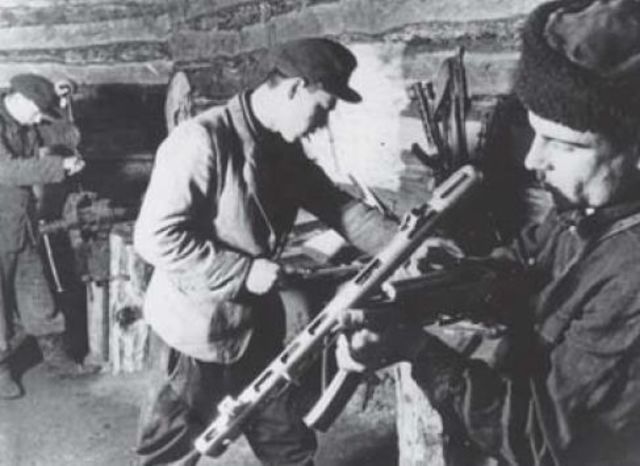 Partisanos revisando y limpiando sus armas en un refugio de madera