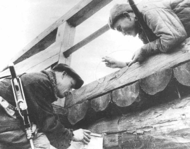 Un par de guerrilleros soviéticos colocando una carga de demolición en un puente de madera